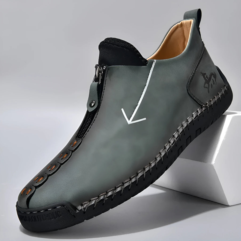 Men's black leather boots with a front zipper and round toe, showing hand-stitched sole detail.