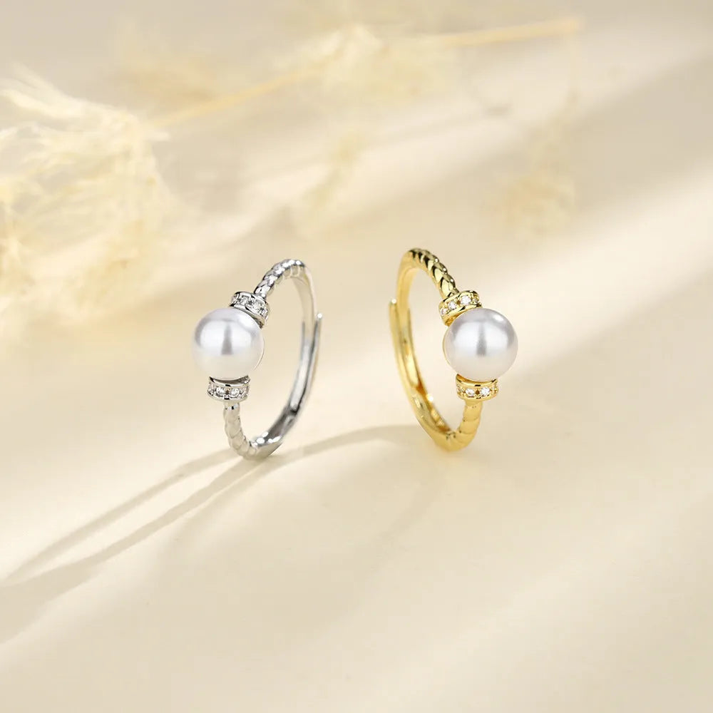Adjustable geometric twist copper ring with a central pearl, shown in gold and silver colour options.
