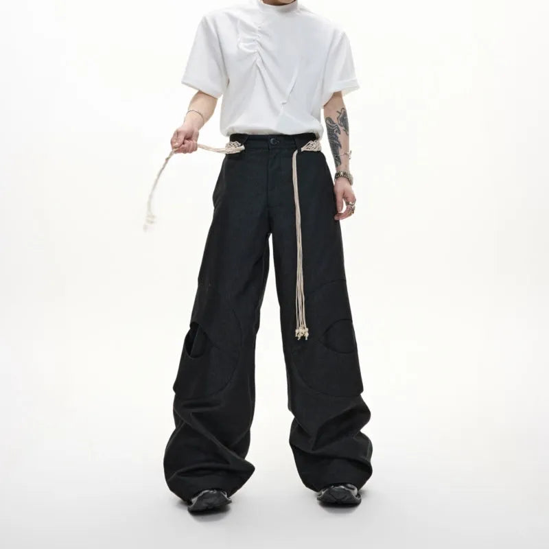Men's dark blue straight-leg trousers showing heavy 3D cutting, belt stitching, and a front placket zipper.