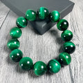 Green tiger eye stone geometric bead bracelet with adjustable closure on a wrist.
