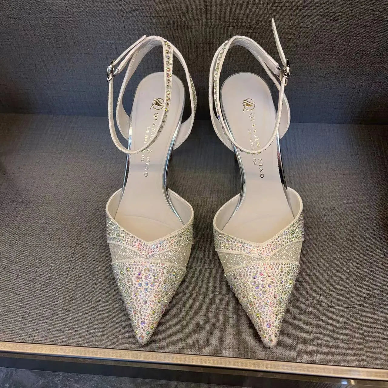 Women's silver high heel shoe with hollow stiletto heel, pointed toe, and bright red sole.
