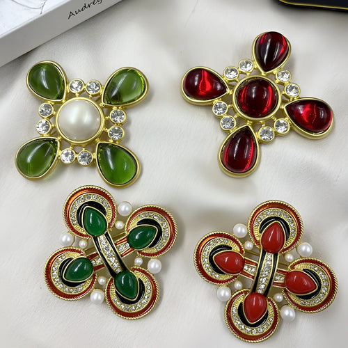 Close-up of a detailed baroque cross brooch with crystal accents on a zinc alloy base.
