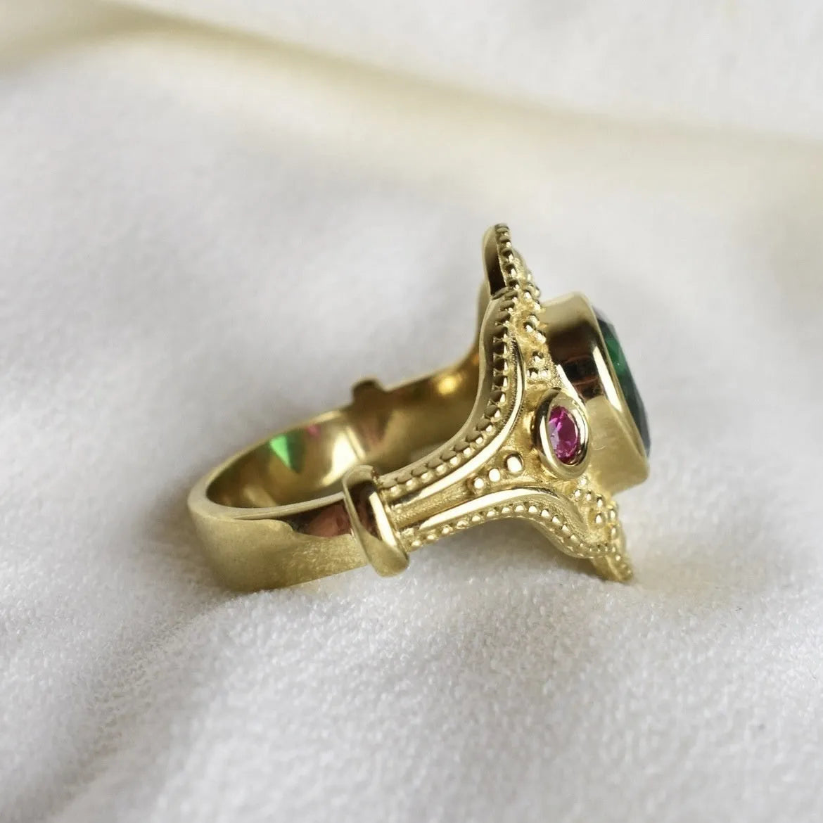 A gold-coloured women's ring with a geometric shape on a plain background.