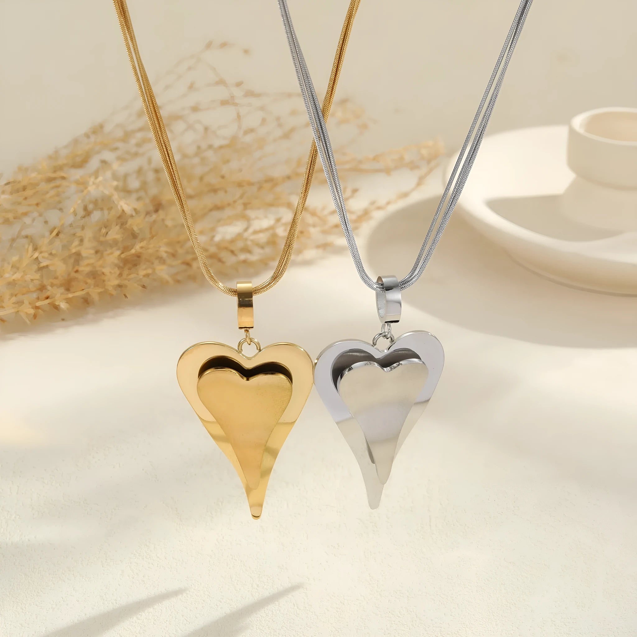 Double heart geometric pendant necklace with snake bones chain in stainless steel, shown in gold and steel colour options.
