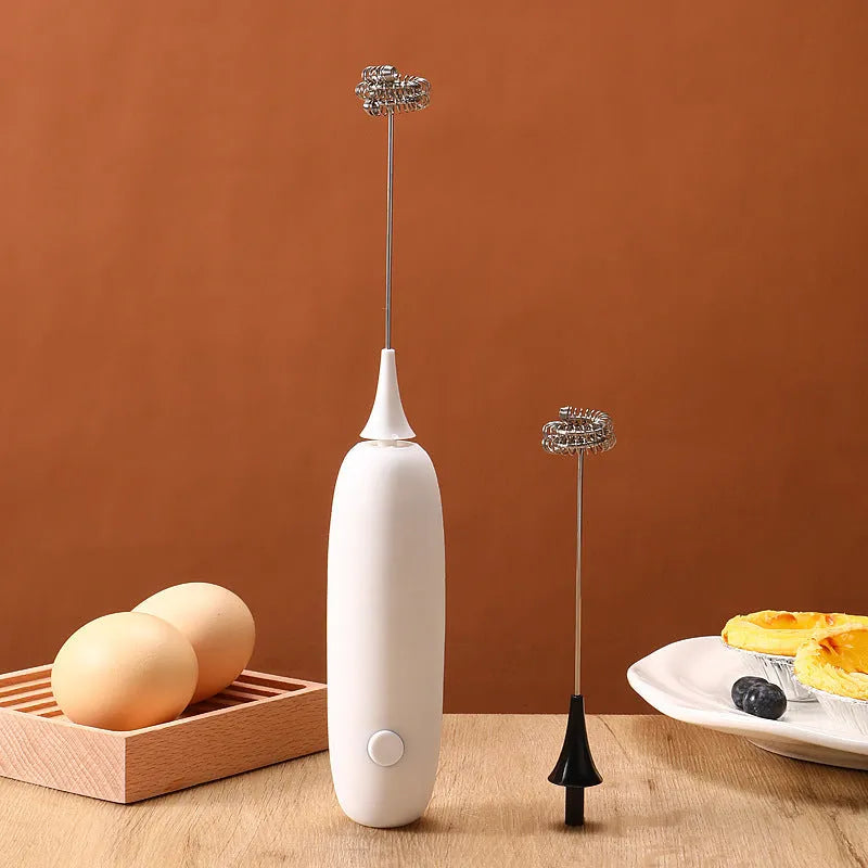 A hand-held electric milk frother in black and white colour options on a kitchen counter.