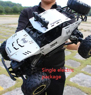Large black or silver 4WD remote control climbing car on off-road terrain with wireless remote.