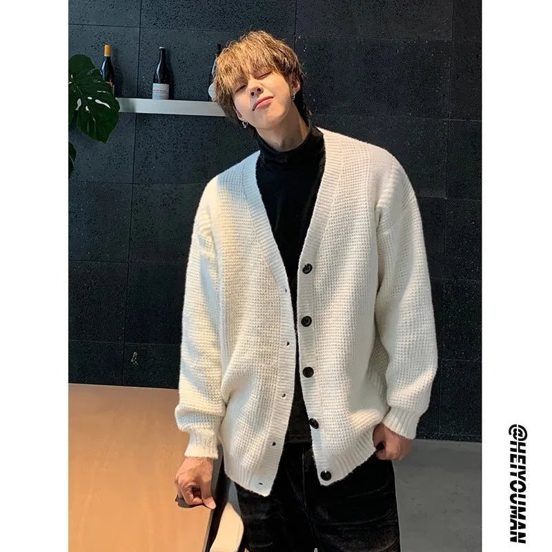 A man's loose-fitting V-neck knitted cardigan in a solid colour on a hanger.