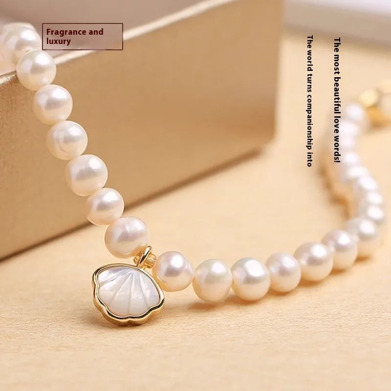 Women's freshwater pearl bracelet with central fan shell design on a wrist, showing elastic and chain fastening options.