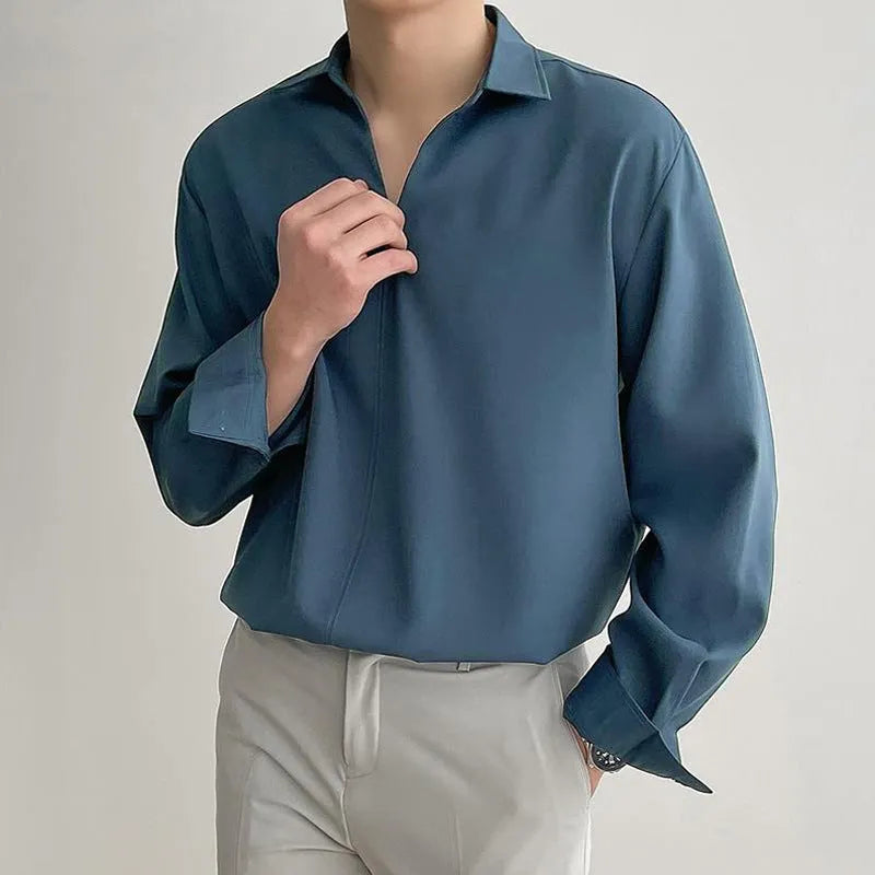 Man wearing a loose fit light business casual shirt in blue, showing lapels and long sleeves.
