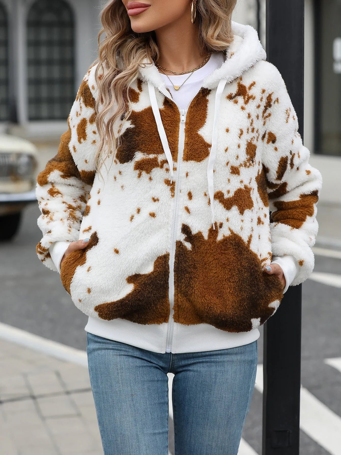 Yellow brown cow print hooded cardigan jacket with front zipper on a model.