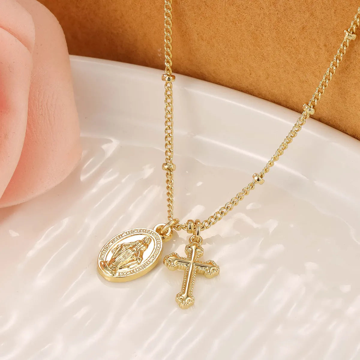 Gold Virgin Mary cross necklace with simple geometric pendant on a chain.