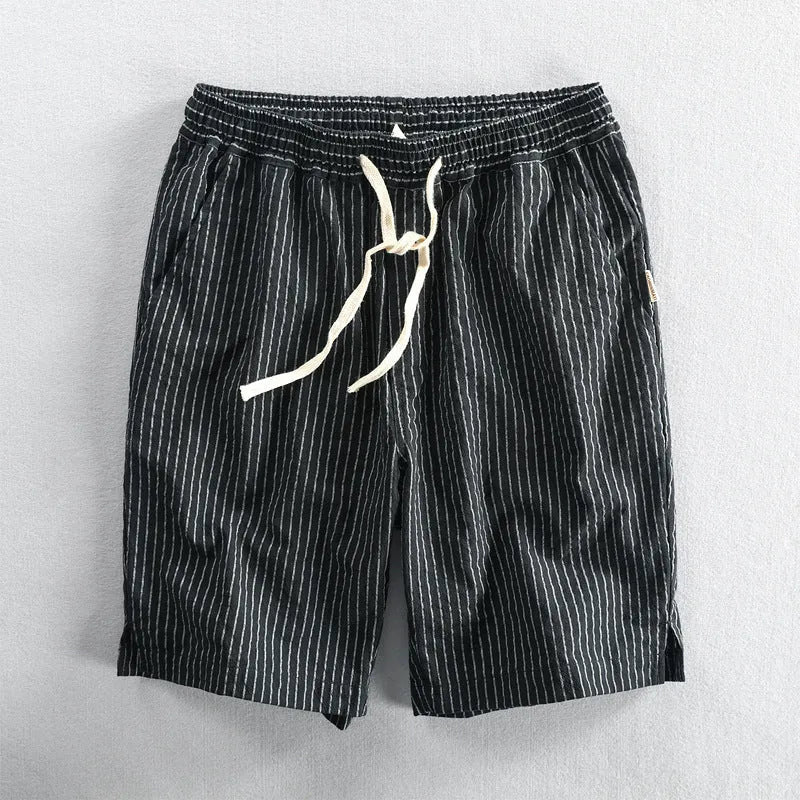 Man wearing striped light blue cotton casual shorts with a mid waist and loose straight fit.