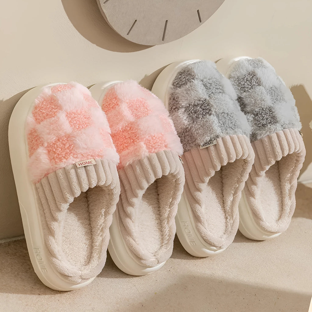 Women's plaid patterned coral velvet indoor slippers with a thick soft sole on a wooden floor.