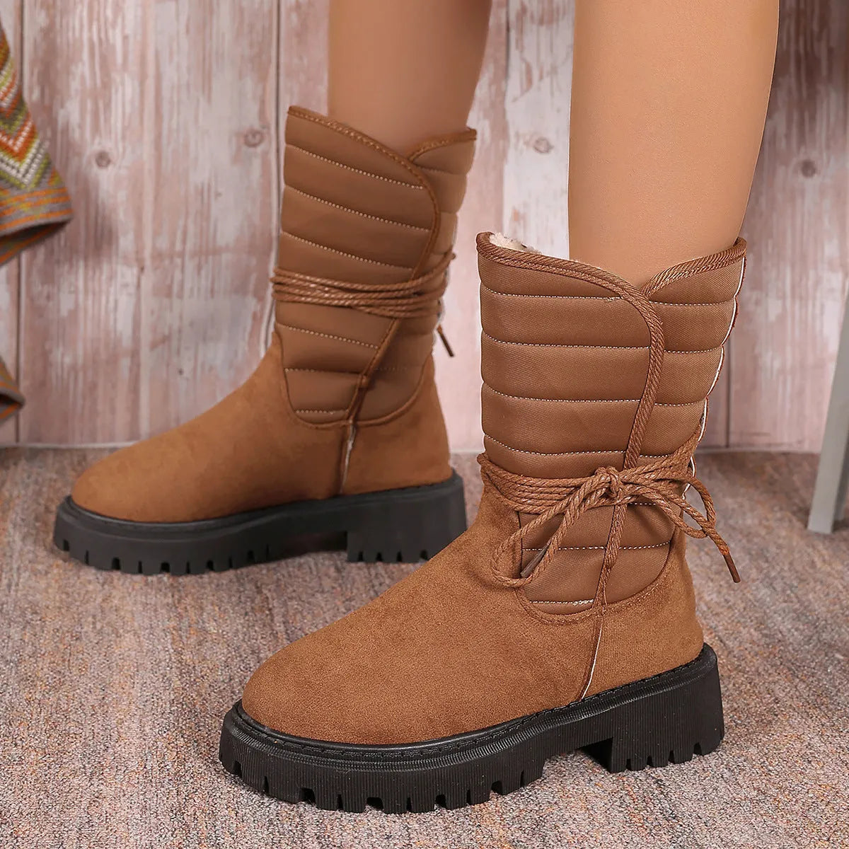 Women's black suede snow boots with chunky heel and lace-up design, shown on a foot.