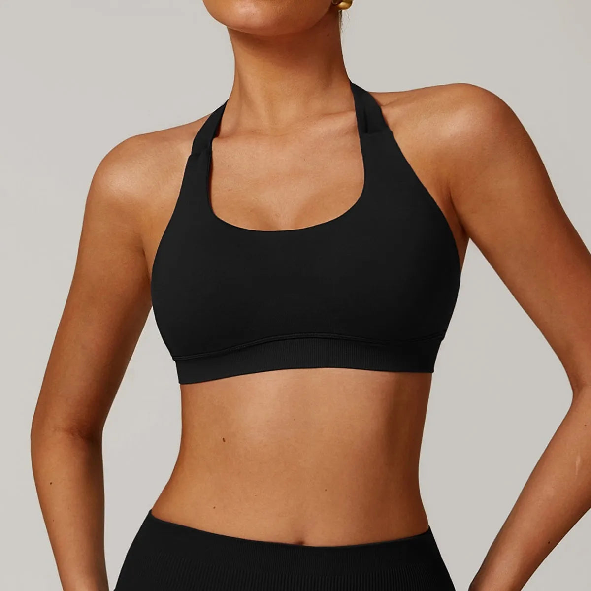 Women's halter-style sports bra in multiple colours, showing hollow back design and removable pads.