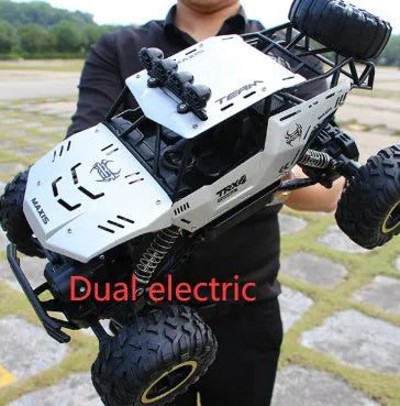 Large black or silver 4WD remote control climbing car on off-road terrain with wireless remote.