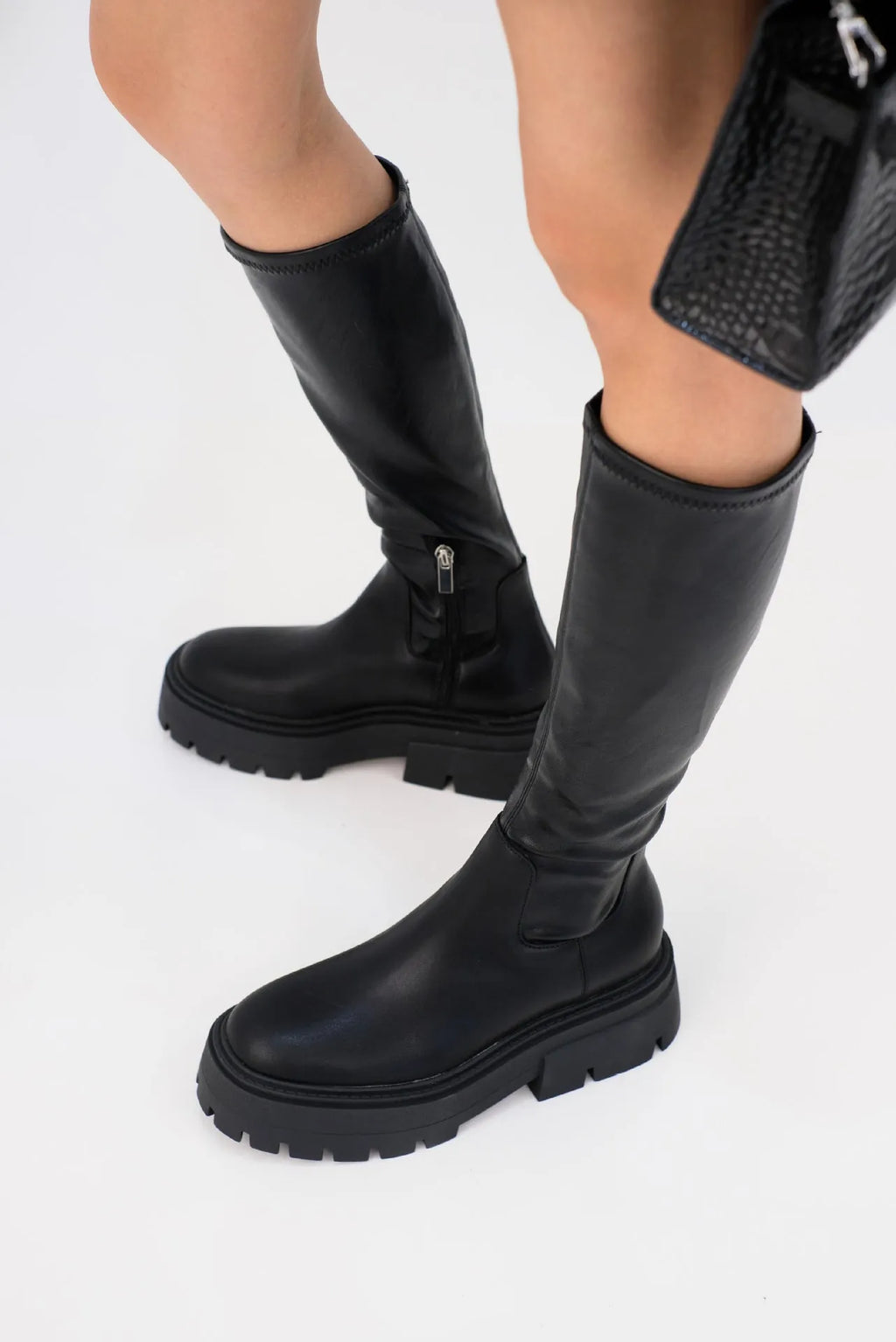 Women's black high leg stretch boots with round toe, non-slip rubber sole, and mid heel on a clean background.