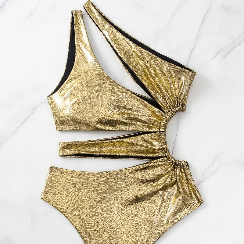 Gold coloured women's backless one-piece swimsuit on a neutral background.