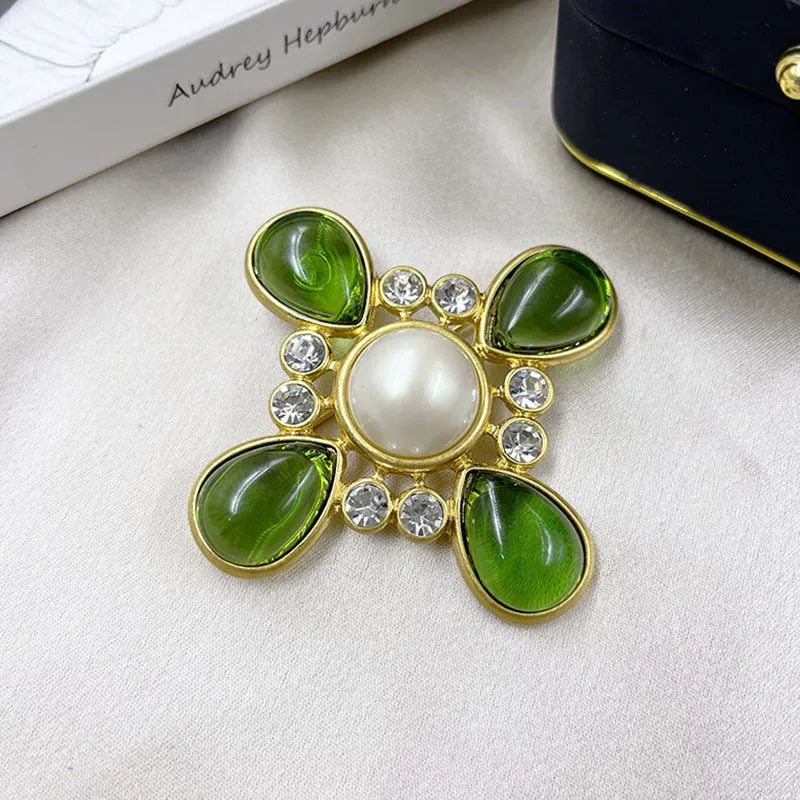 Close-up of a detailed baroque cross brooch with crystal accents on a zinc alloy base.