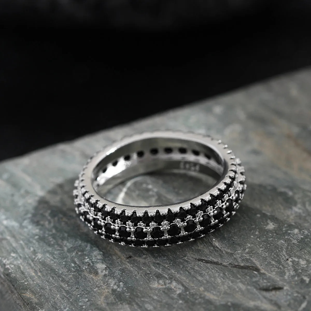 Geometric gang drill style engagement ring with a triangular zircon stone inlay on a metal band.