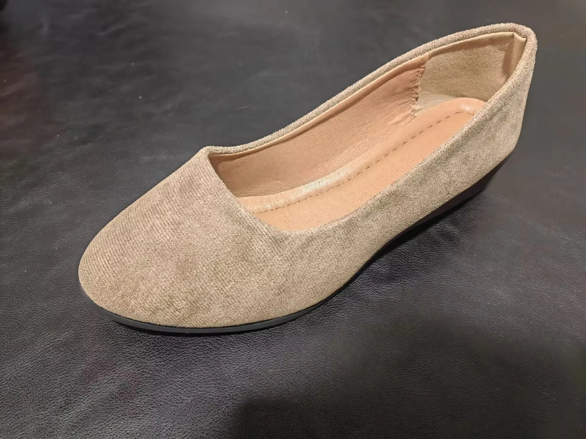 Women's black suede low wedge pumps with pointed toe and shallow mouth design on a rubber sole.