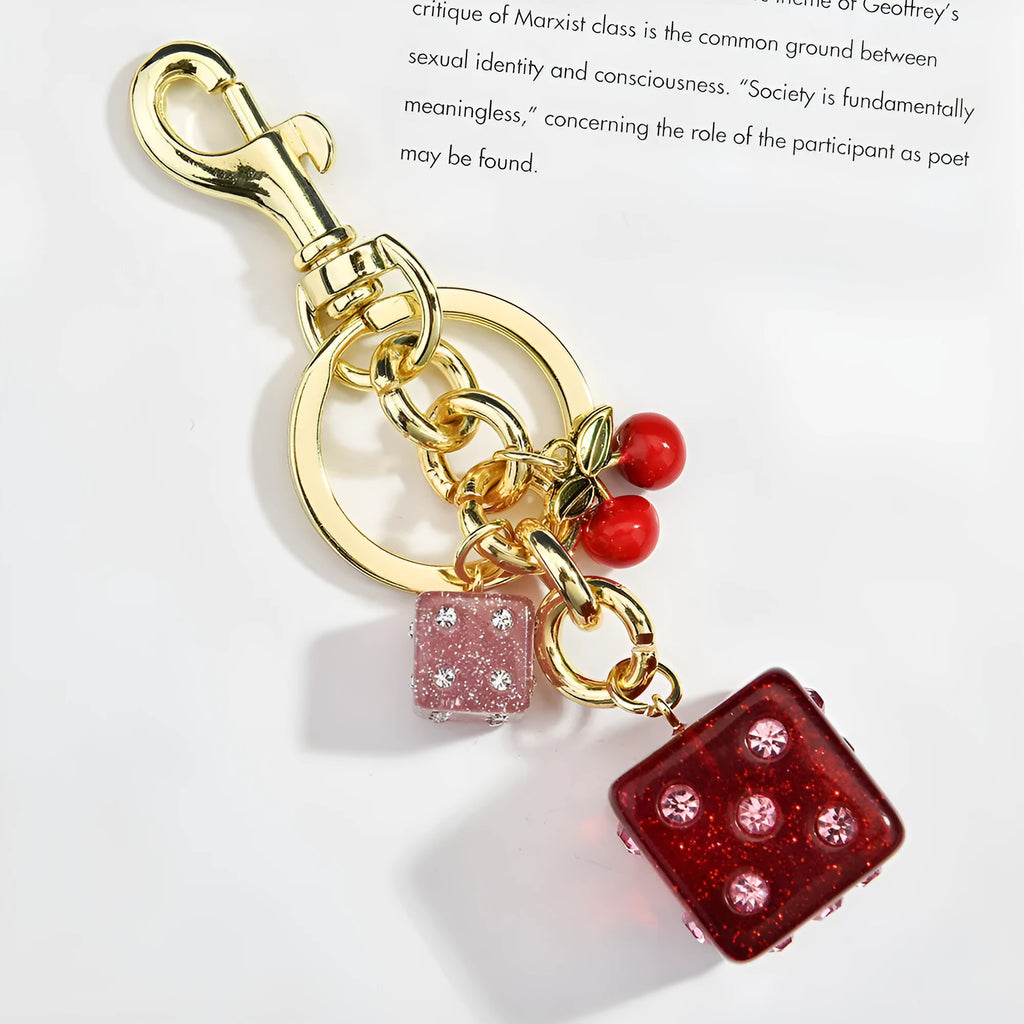 Square metal keychain pendant with a cerise two-tone dice pattern.