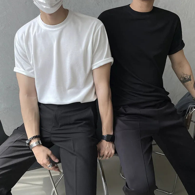 A man wearing a slim fit black cotton T-shirt with a round neck and half sleeves.