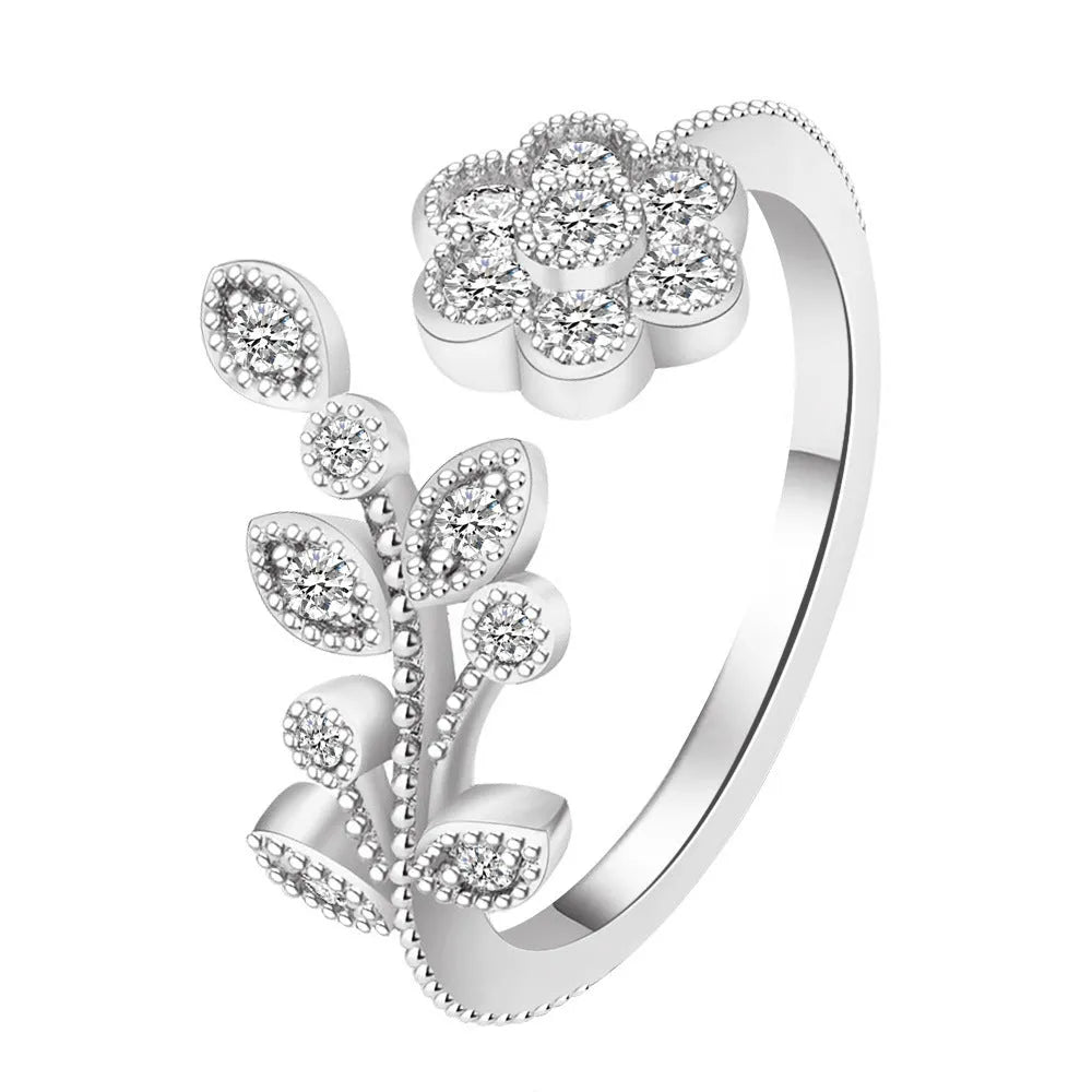 Women's open ring made of copper with a diamond finish, shaped as a detailed flower with leaves, shown in gold and white colour options.