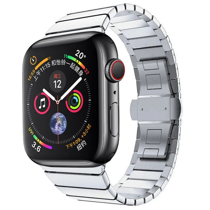 Silver metal Apple Watch strap with butterfly buckle on a wrist, showing the clasp closed.