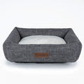 Grey plaid linen square dog bed for medium-sized dogs on a wooden floor.