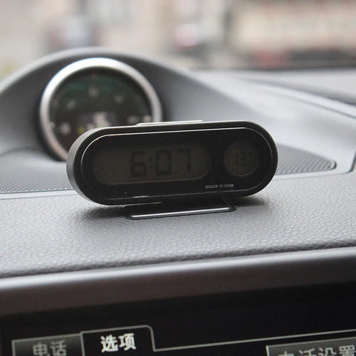 Black electronic car dashboard clock with LED display showing time and temperature