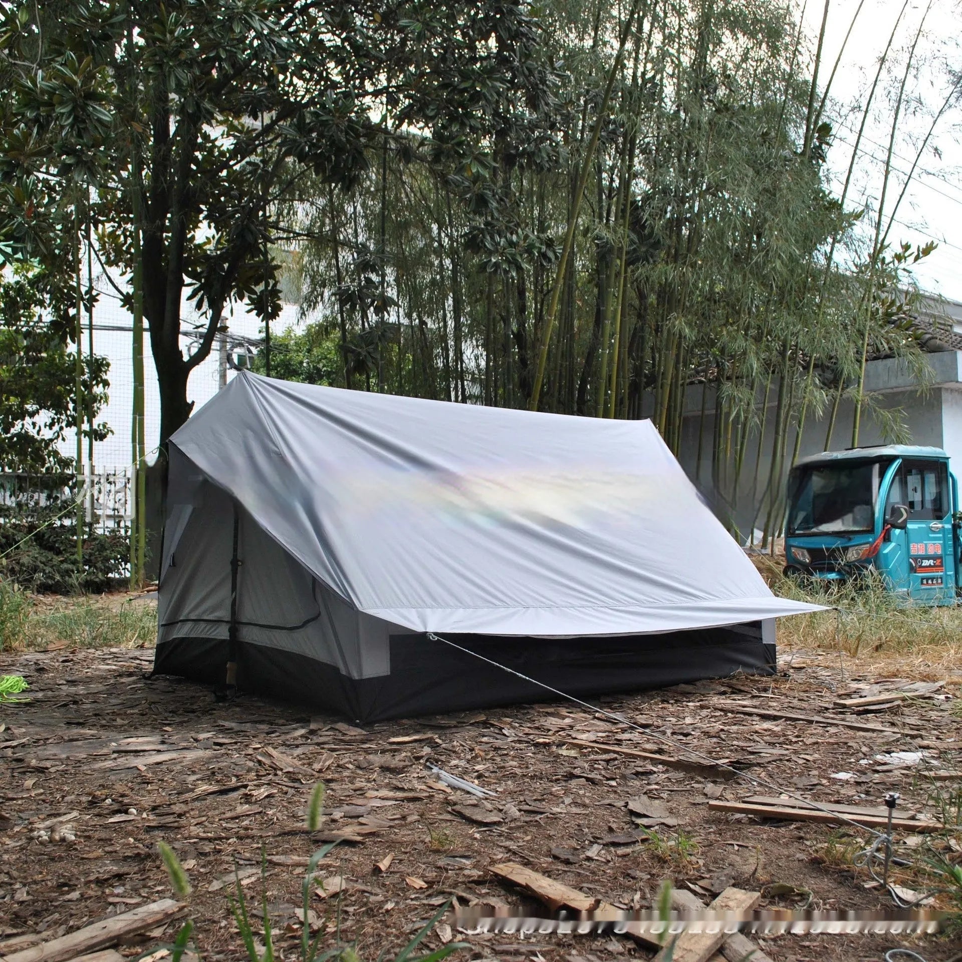 Brown or white A-line hiking tent without poles, supported by hiking canes