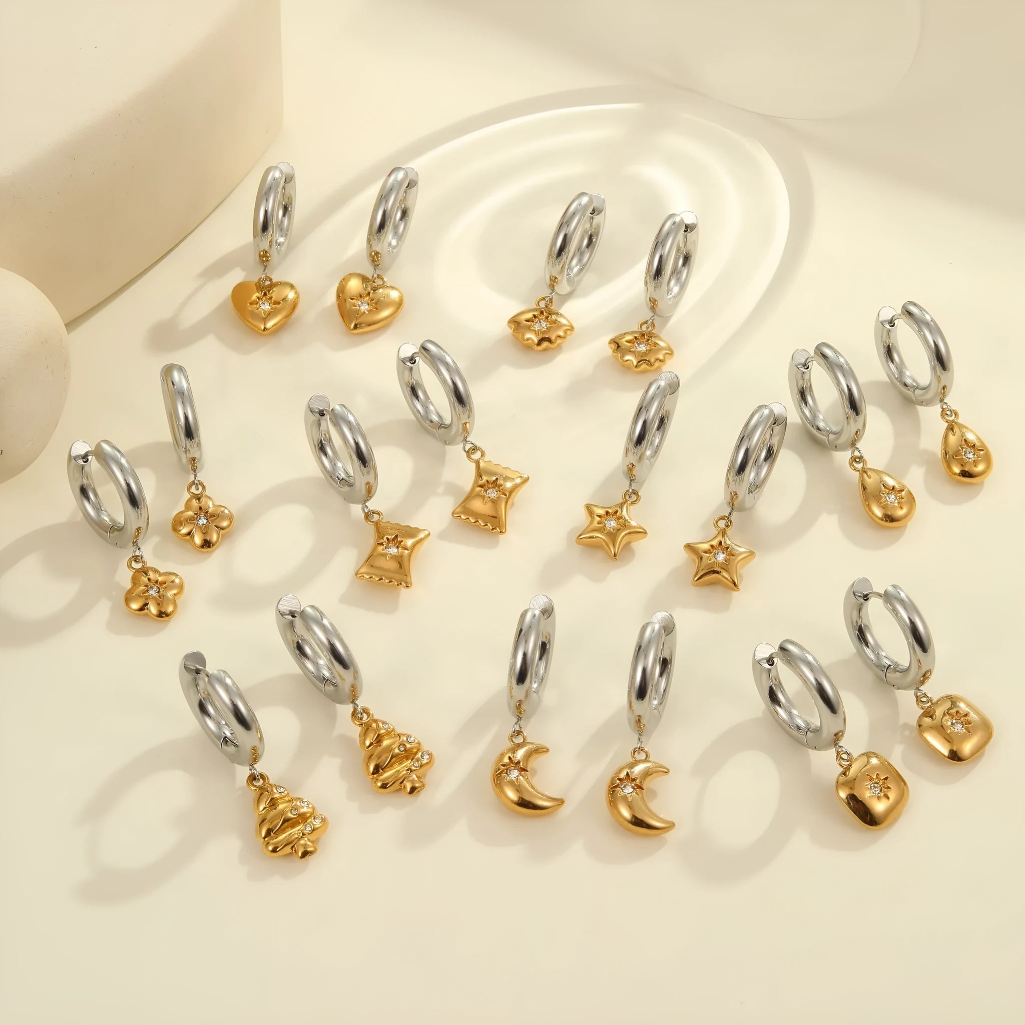 A pair of stainless steel earrings with an 18K gold colour finish, shown in a Christmas tree shape and a heart shape.