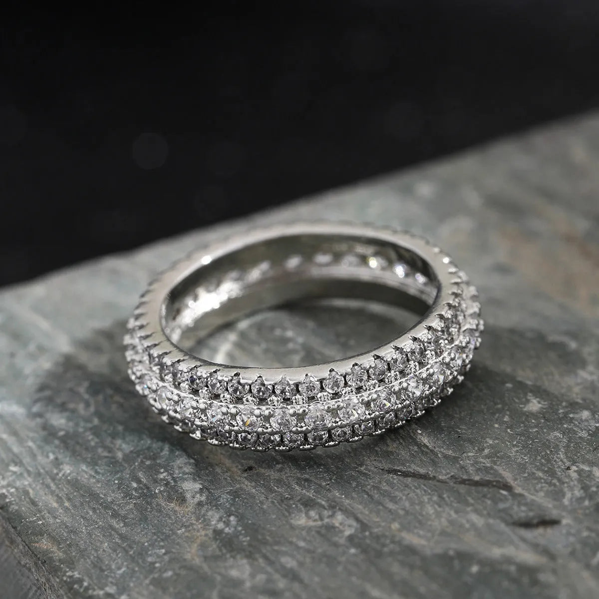 Geometric gang drill style engagement ring with a triangular zircon stone inlay on a metal band.