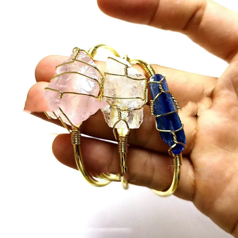 Natural rough crystal bracelet with geometric gold metal winding on a wrist.