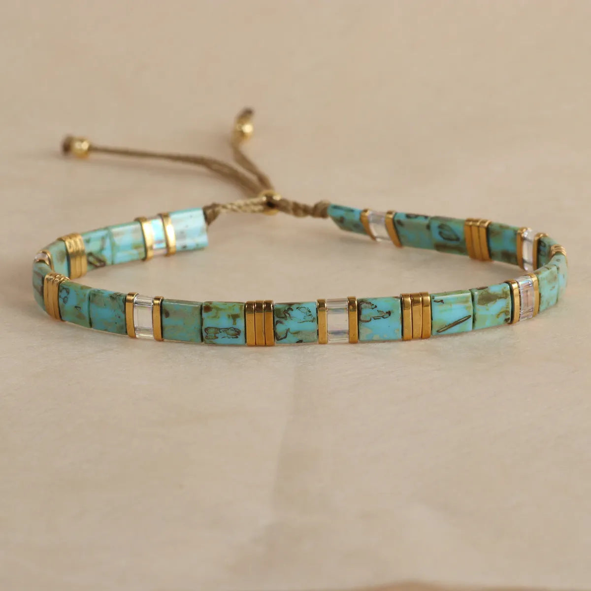 Adjustable pull beads bracelet with glass and coloured glaze beads in geometric and round shapes
