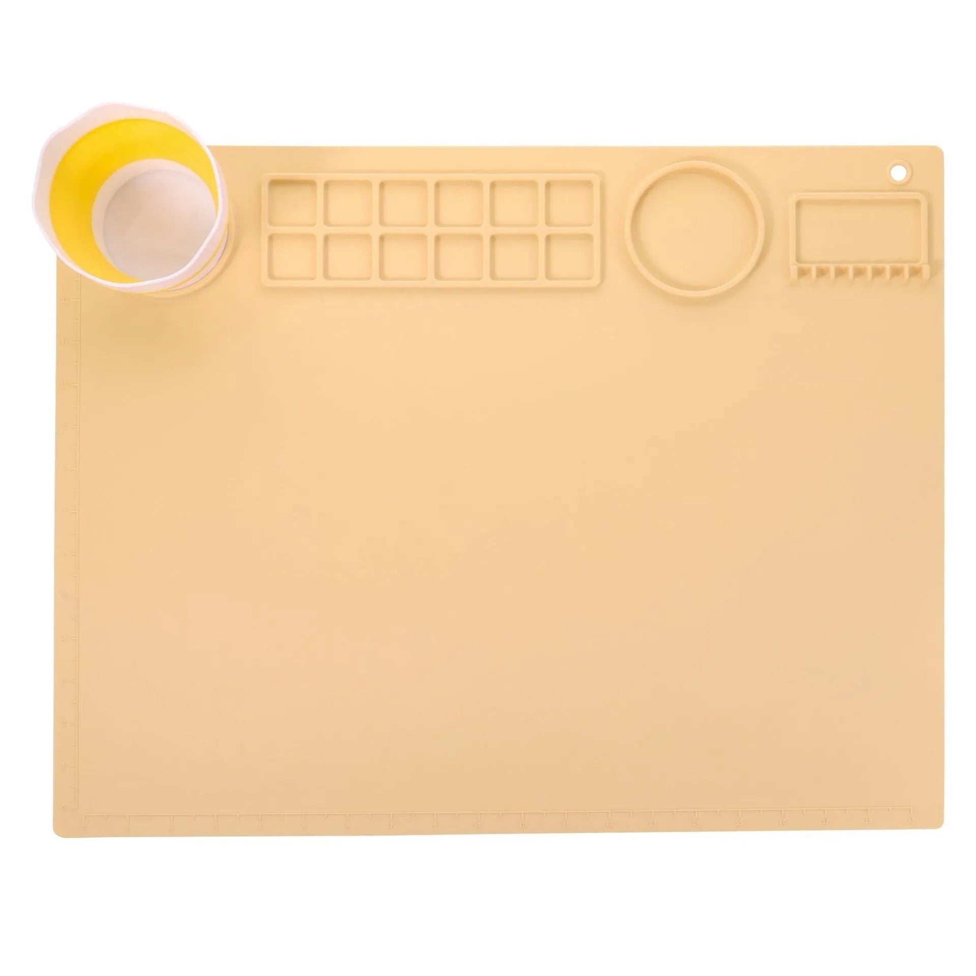 Light blue silicone painting mat with an integrated bowl on one side, positioned on a wooden table.