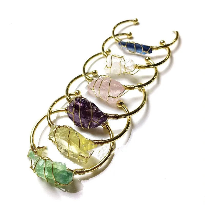 Natural rough crystal bracelet with geometric gold metal winding on a wrist.