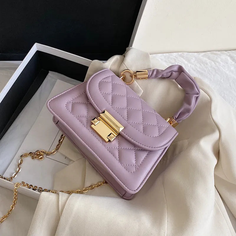 Purple rhombus-shaped small square shoulder bag with crossbody strap against neutral background
