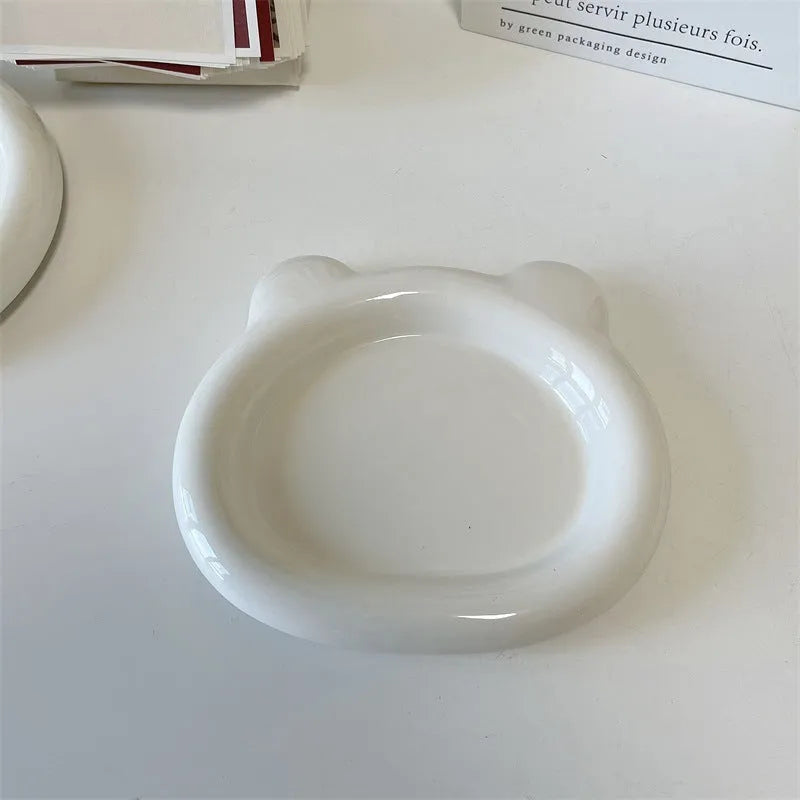 White porcelain round plate with chubby toot bear doodle pattern, shown as a plant saucer.