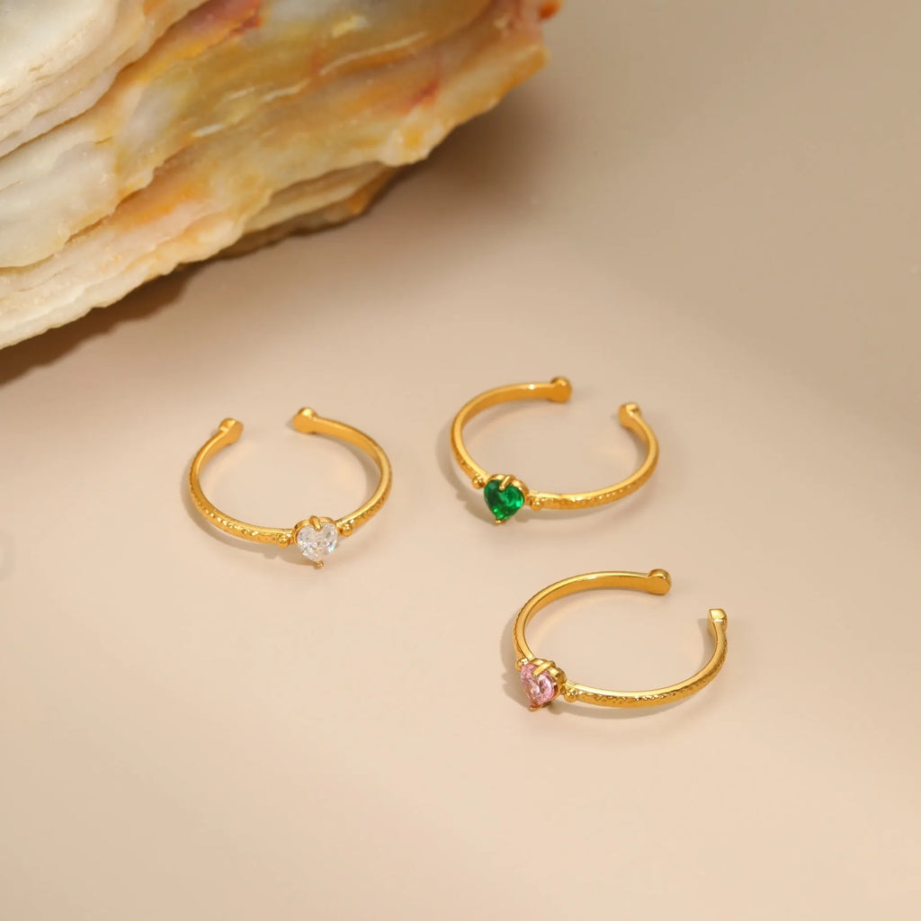 Open ended stainless steel ring with a geometric heart shape and inlaid zircon stone in white, pink, or green.