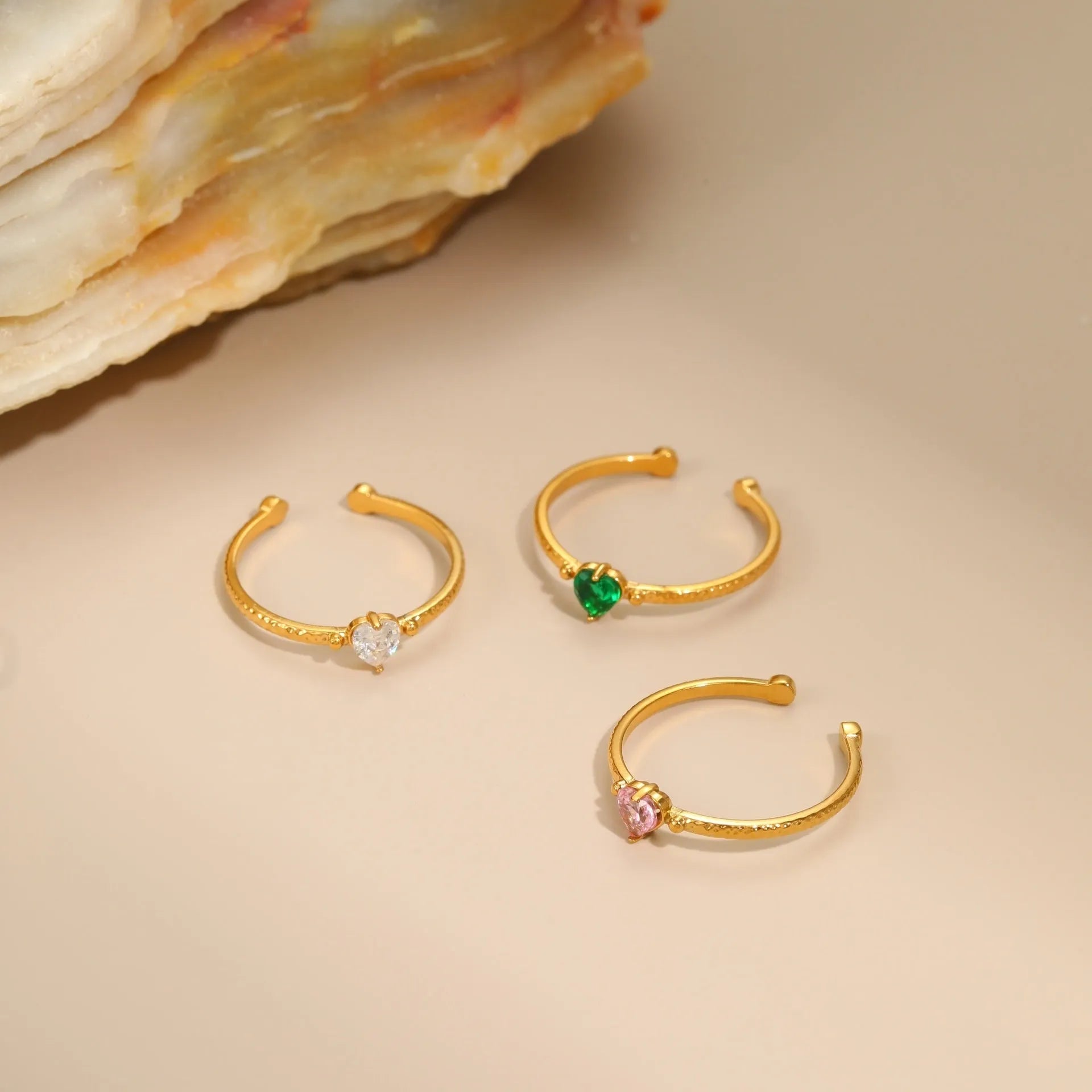 Open ended stainless steel ring with a geometric heart shape and inlaid zircon stone in white, pink, or green.