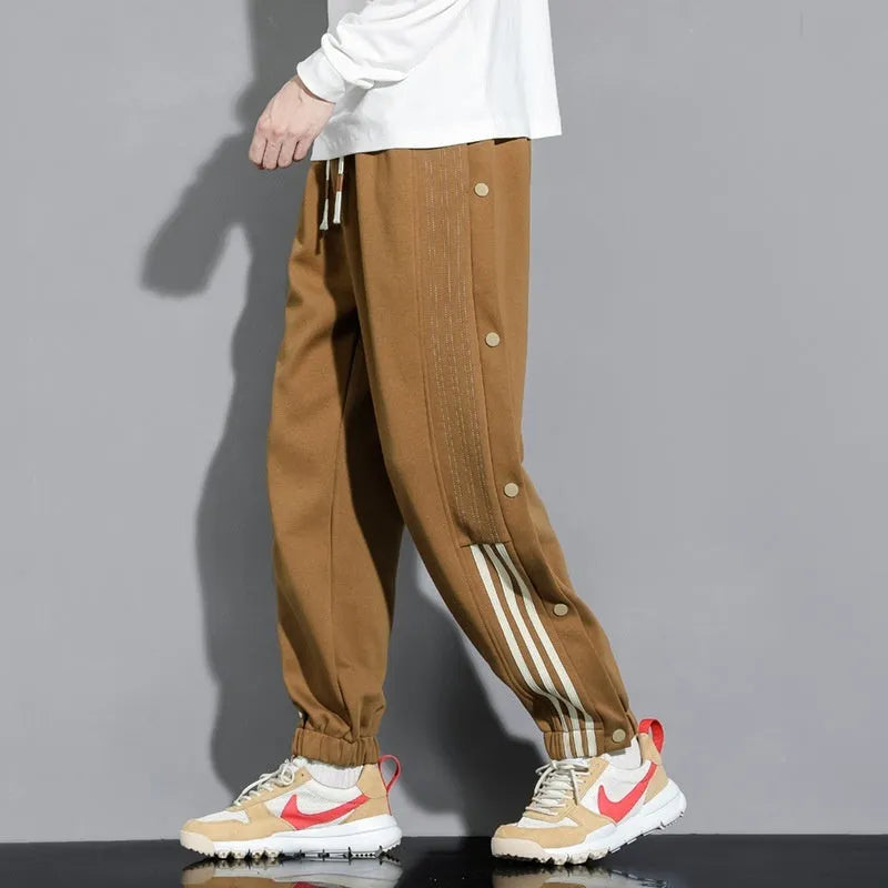 Men's black loose-fit sweatpants with ankle ties and a drawstring high waist on a neutral background.