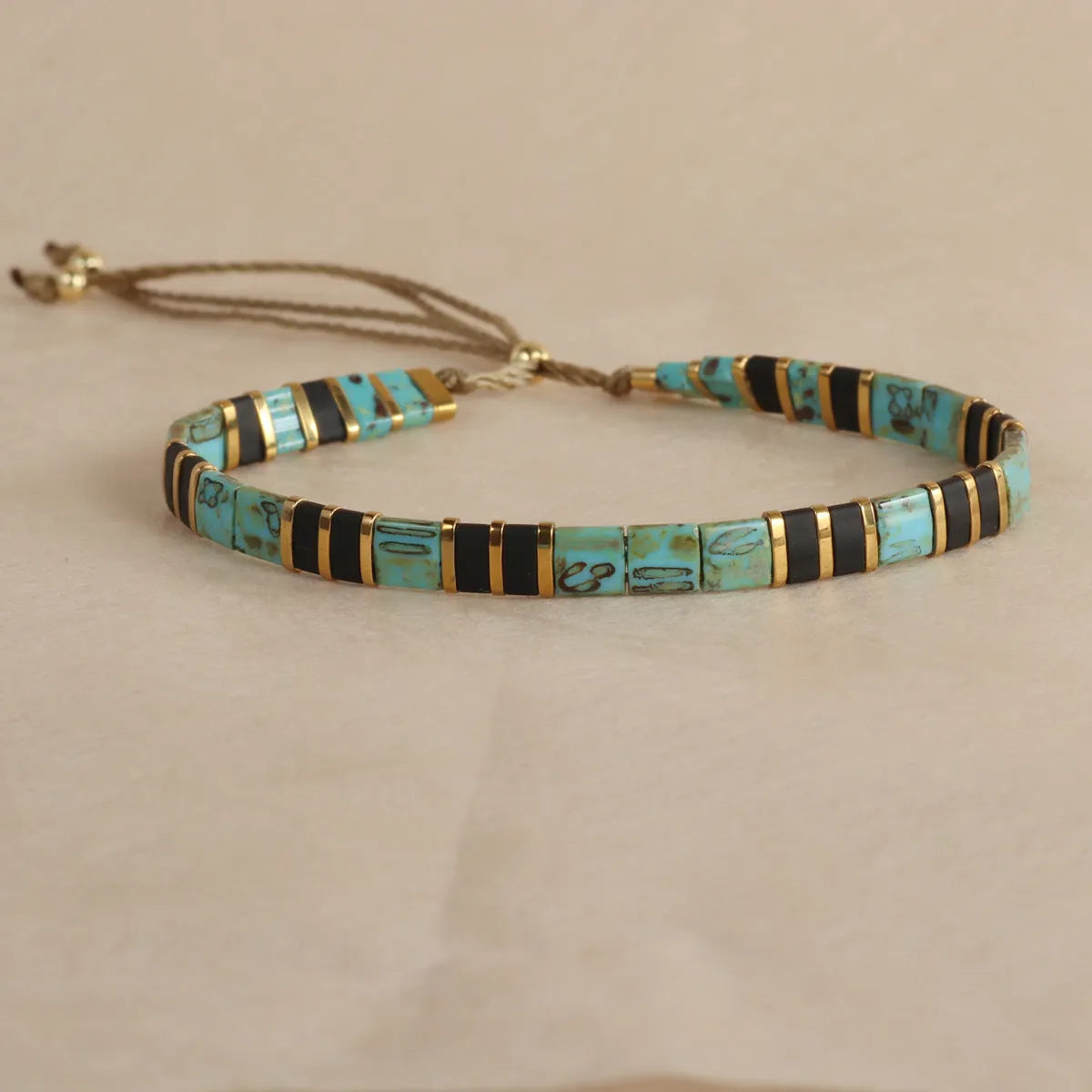 Adjustable pull beads bracelet with glass and coloured glaze beads in geometric and round shapes