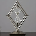 Modern zinc alloy hourglass timer on desk showing bronze frame with white sand.