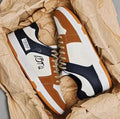 Simple white and blue lace-up sneakers on a plain background, showing the wear-resistant sole and classic design.