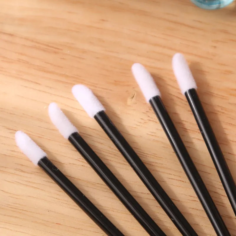 Pack of disposable lip brush applicators with flocked heads and black handles on a white background.