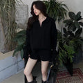Women's creamy-white knitted suit set with cable knit pattern, long sleeve top, and elastic waist shorts.