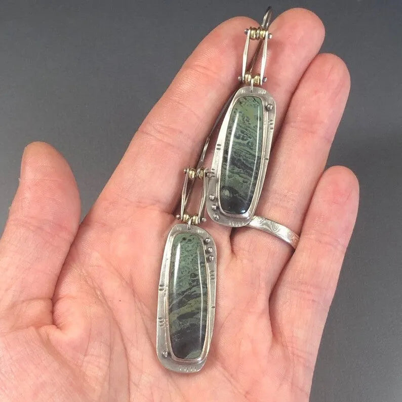 Close-up of women's geometric alloy earrings with a white and grey marble pattern.