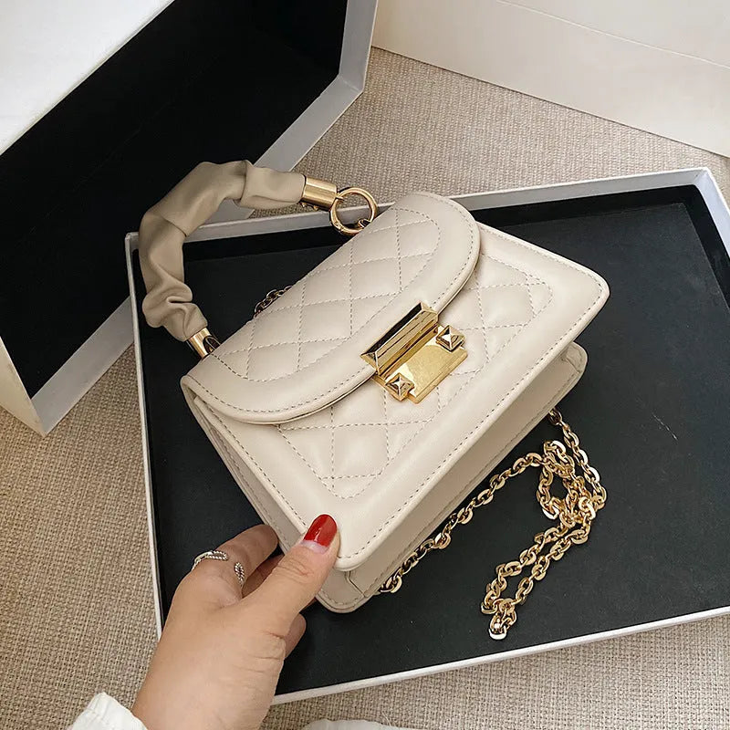 Purple rhombus-shaped small square shoulder bag with crossbody strap against neutral background